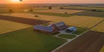 Aerial view of a modern US farm with precision agriculture, drones, and autonomous tractors at sunrise.